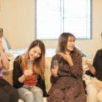 4 women talking while holding a wine